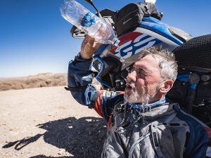 Afrikabiker Motorradfahrer in der Wüste mit Wasser